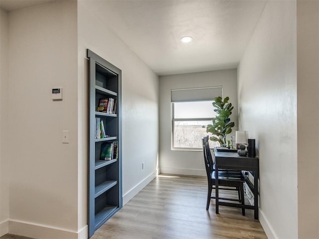 home office with built in features, baseboards, and wood finished floors