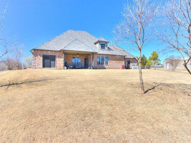 back of house featuring brick siding, an attached carport, a lawn, and fence