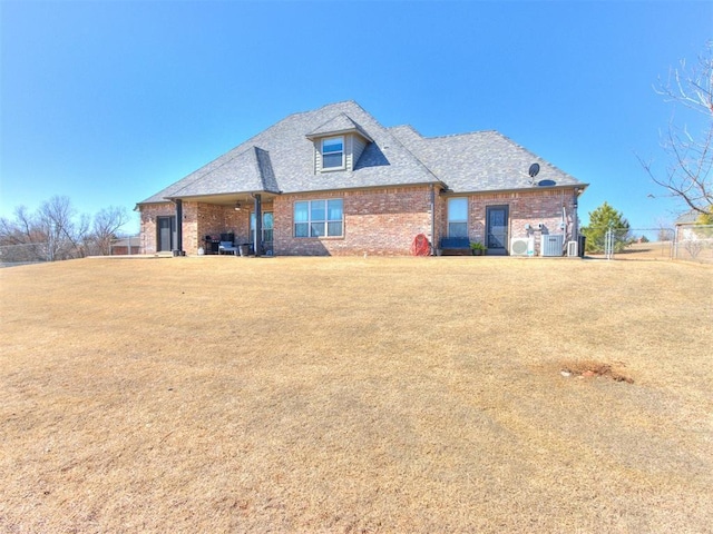 view of front of property featuring a front yard, cooling unit, fence, and brick siding