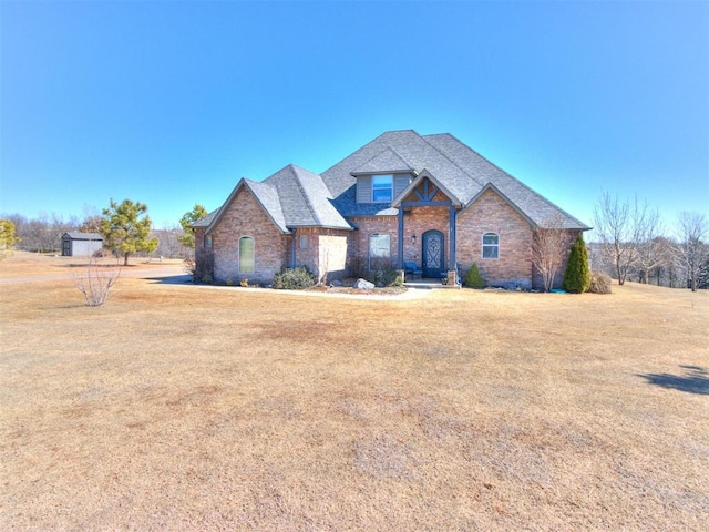 view of front of house with a front yard, brick siding, and stone siding