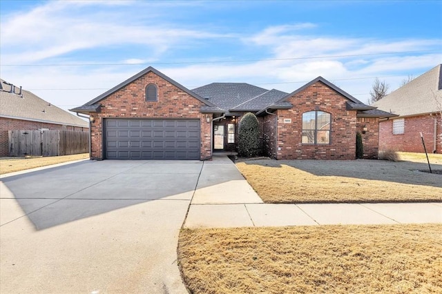 view of front of house featuring brick siding, a shingled roof, concrete driveway, fence, and a garage