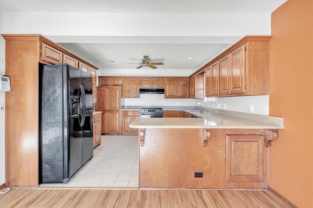 kitchen featuring electric stove, a peninsula, black refrigerator with ice dispenser, light countertops, and under cabinet range hood