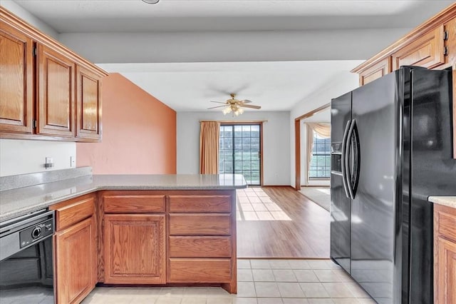 kitchen featuring a peninsula, black appliances, ceiling fan, and brown cabinetry