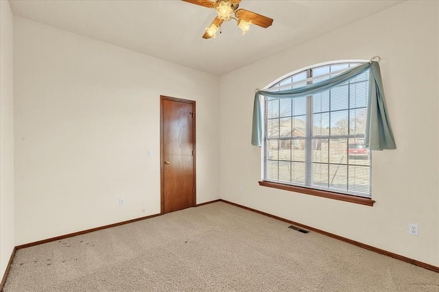 carpeted empty room featuring a ceiling fan, visible vents, and baseboards