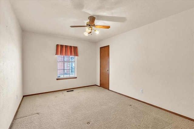 spare room featuring light carpet, ceiling fan, visible vents, and baseboards