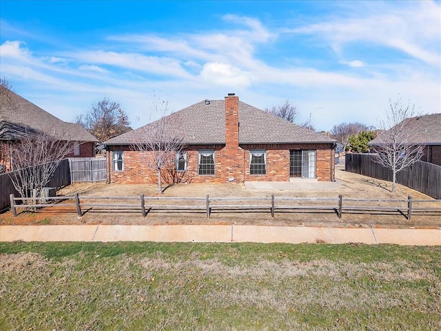 view of front of property featuring roof with shingles, brick siding, a chimney, and fence private yard