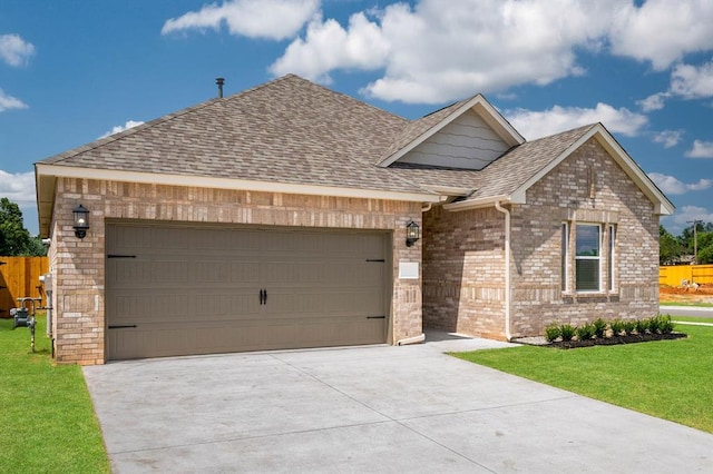 view of front facade featuring a garage, driveway, roof with shingles, a front yard, and brick siding