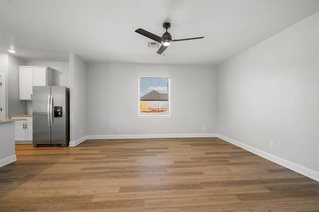 interior space featuring ceiling fan, light wood-type flooring, visible vents, and baseboards