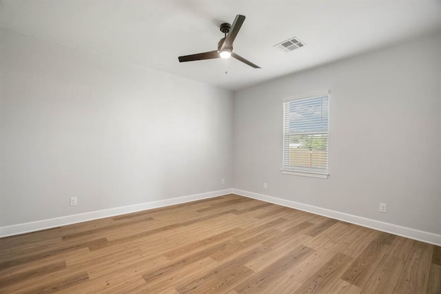 empty room with ceiling fan, light wood-type flooring, visible vents, and baseboards