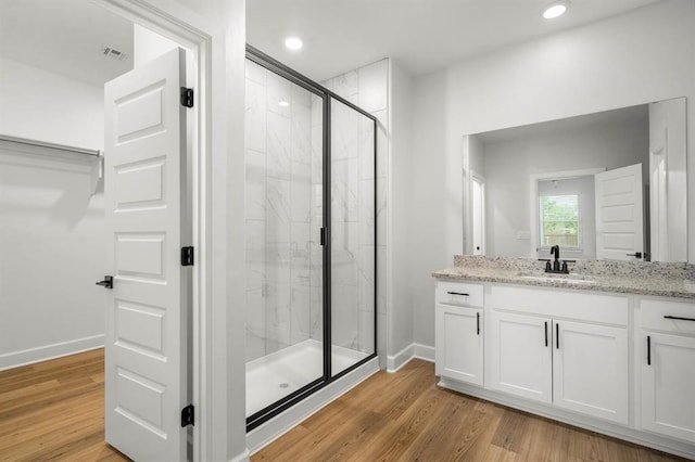 full bath with a marble finish shower, visible vents, wood finished floors, and vanity