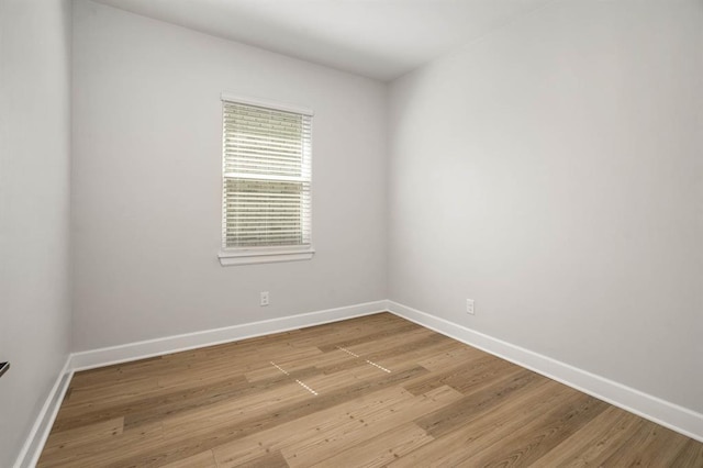 spare room with baseboards and light wood finished floors