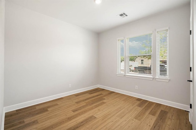 unfurnished room featuring visible vents, light wood-style flooring, and baseboards