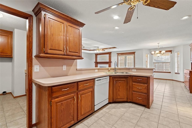 kitchen featuring dishwasher, brown cabinets, a peninsula, light countertops, and a sink