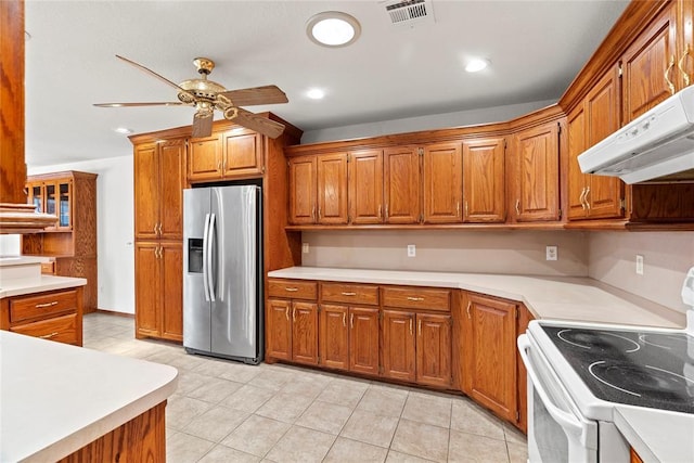 kitchen with brown cabinets, white electric stove, stainless steel refrigerator with ice dispenser, visible vents, and under cabinet range hood