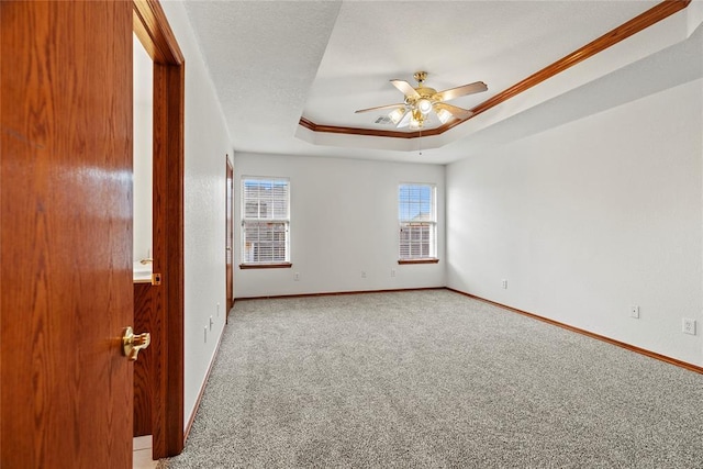 unfurnished room with a textured ceiling, ceiling fan, carpet floors, baseboards, and a tray ceiling