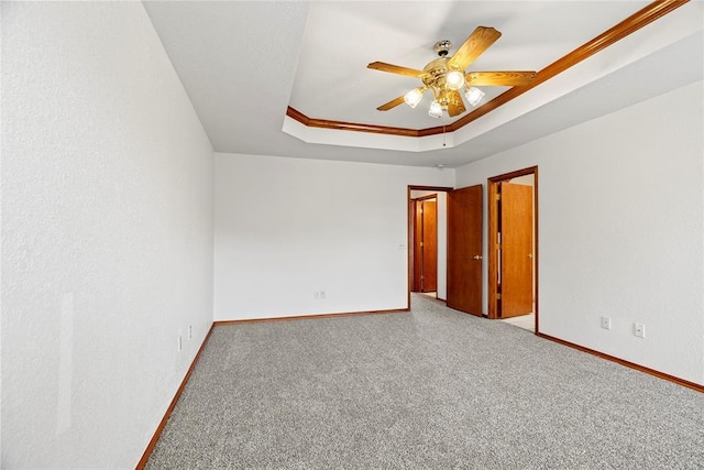 unfurnished room with a ceiling fan, baseboards, a tray ceiling, and carpet flooring