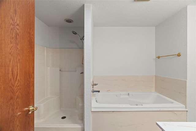 full bathroom with a textured ceiling, a textured wall, a jetted tub, and walk in shower