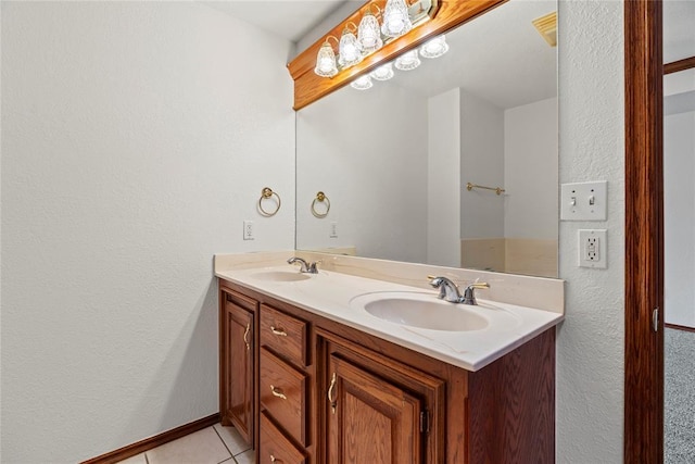 bathroom with double vanity, baseboards, a sink, and tile patterned floors