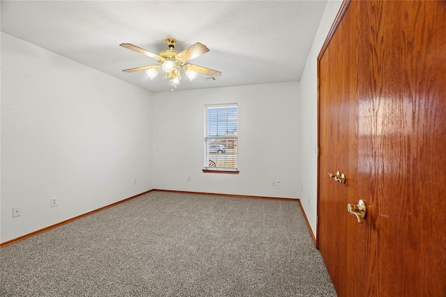 empty room with carpet flooring, a ceiling fan, and baseboards