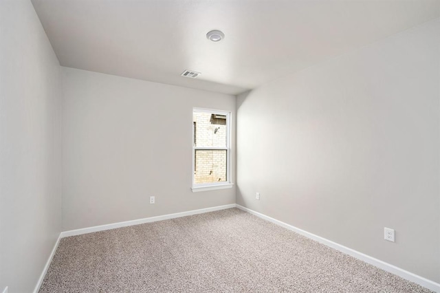 empty room featuring carpet floors, visible vents, and baseboards