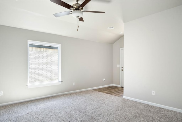 carpeted spare room featuring lofted ceiling, ceiling fan, visible vents, and baseboards