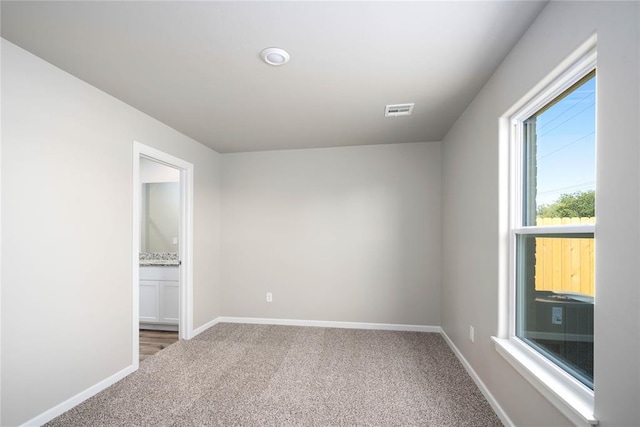 carpeted empty room featuring visible vents and baseboards