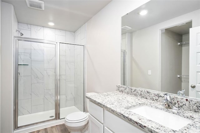 full bathroom with toilet, a stall shower, vanity, and visible vents