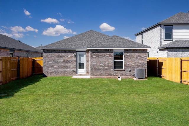 rear view of house with a fenced backyard, a lawn, and roof with shingles