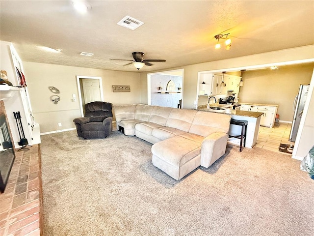 living area with light carpet, a fireplace, visible vents, and a ceiling fan