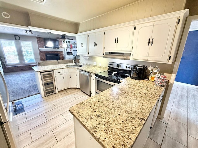 kitchen featuring under cabinet range hood, beverage cooler, a peninsula, a sink, and appliances with stainless steel finishes