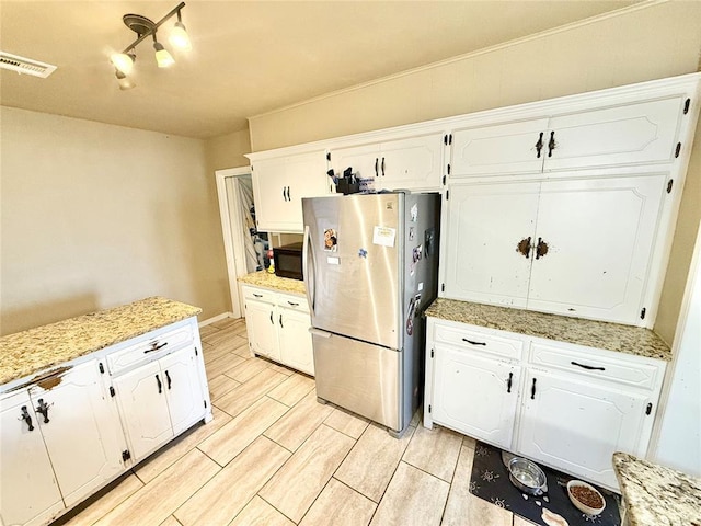 kitchen featuring white cabinets, visible vents, wood finish floors, and freestanding refrigerator