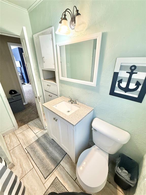 bathroom featuring vanity, crown molding, and a textured wall