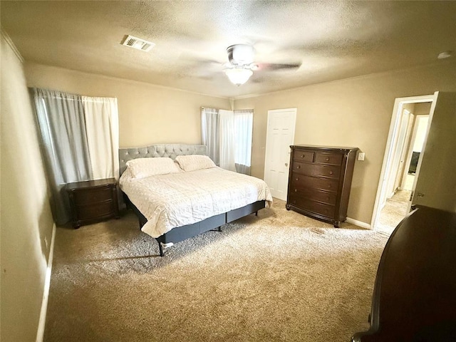 carpeted bedroom featuring baseboards, ceiling fan, visible vents, and a textured ceiling