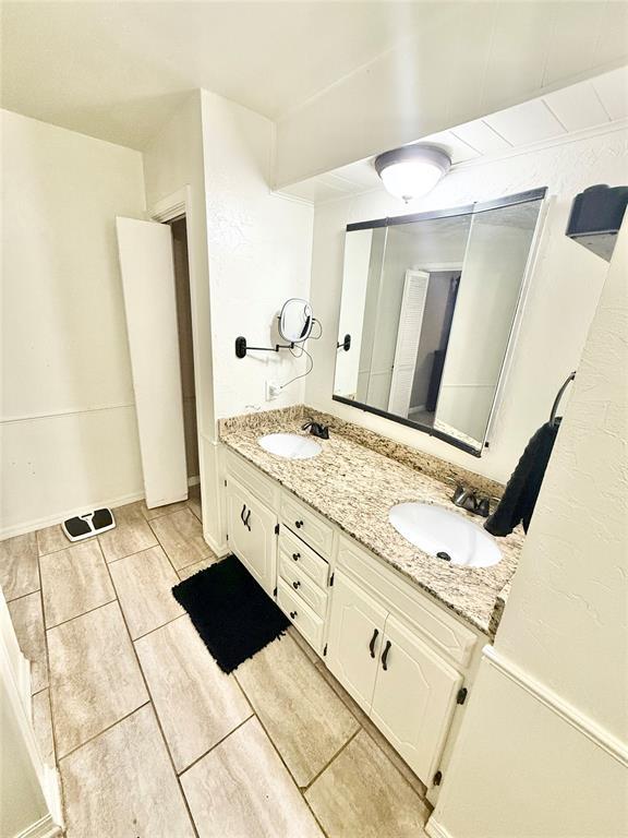 bathroom featuring double vanity, a sink, and baseboards