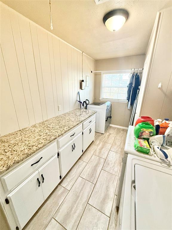 washroom with wood finish floors, cabinet space, independent washer and dryer, and a textured ceiling