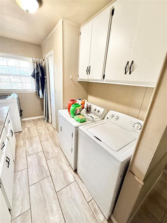 clothes washing area featuring cabinet space and washer and clothes dryer