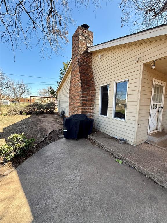 view of side of home featuring a chimney, a patio area, and fence