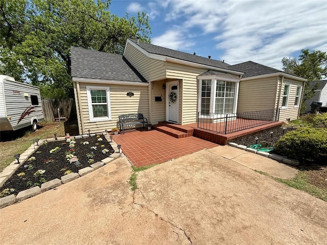 bungalow with a patio area and roof with shingles