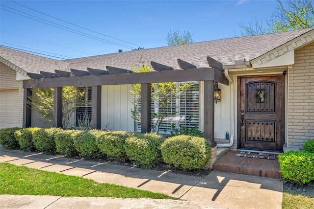 entrance to property with brick siding, a pergola, and roof with shingles