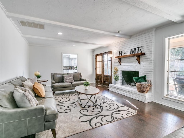 living room with a fireplace, beam ceiling, dark wood-style floors, and visible vents