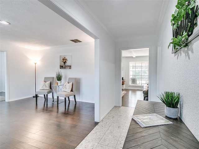 interior space featuring visible vents, wood finished floors, baseboards, and ornamental molding