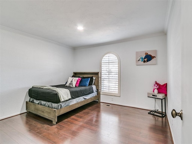 bedroom featuring crown molding, wood finished floors, and baseboards