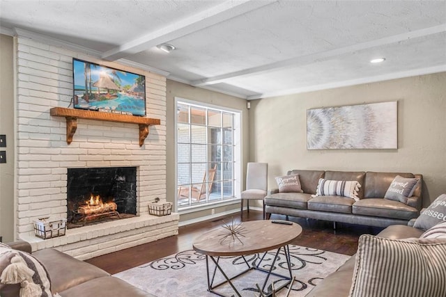 living room with beam ceiling, ornamental molding, a textured ceiling, wood finished floors, and a fireplace