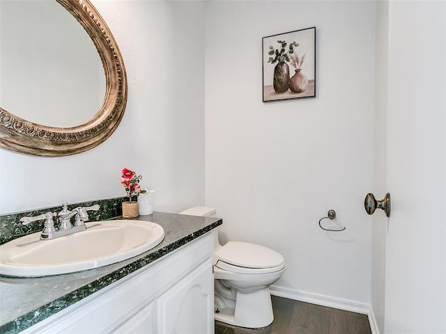 bathroom featuring toilet, vanity, baseboards, and wood finished floors