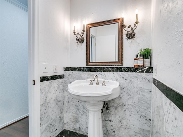 bathroom featuring a wainscoted wall, tile walls, and wood finished floors