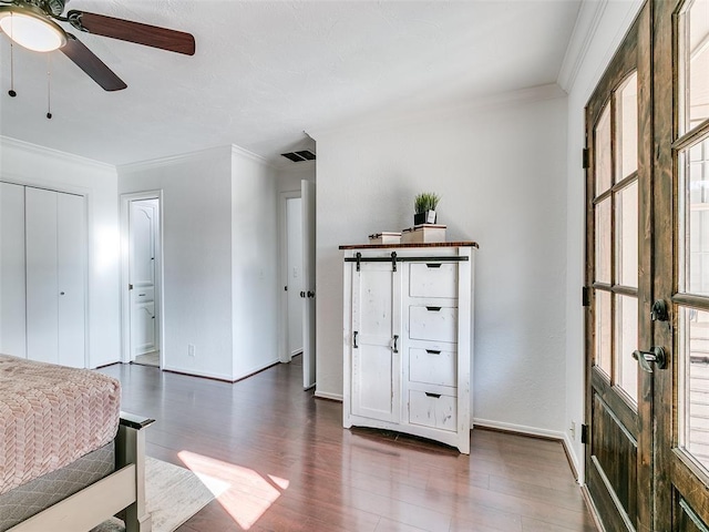 bedroom with a ceiling fan, visible vents, baseboards, dark wood finished floors, and ornamental molding