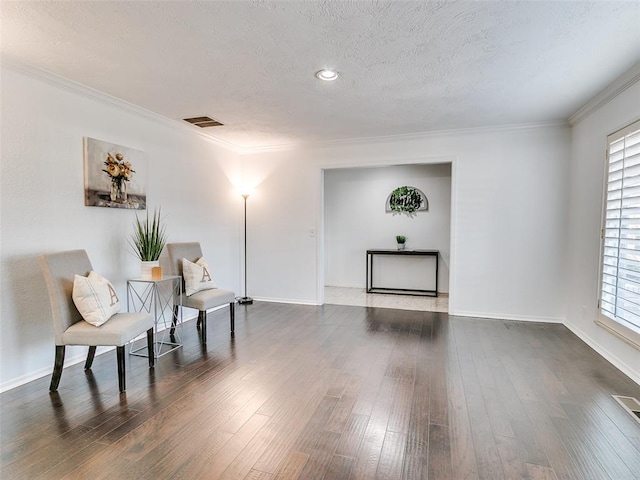 sitting room with visible vents, plenty of natural light, a textured ceiling, and wood finished floors