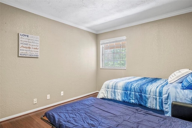 bedroom with a textured ceiling, baseboards, a textured wall, and wood finished floors