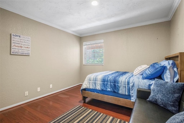 bedroom featuring ornamental molding, a textured ceiling, wood finished floors, baseboards, and a textured wall