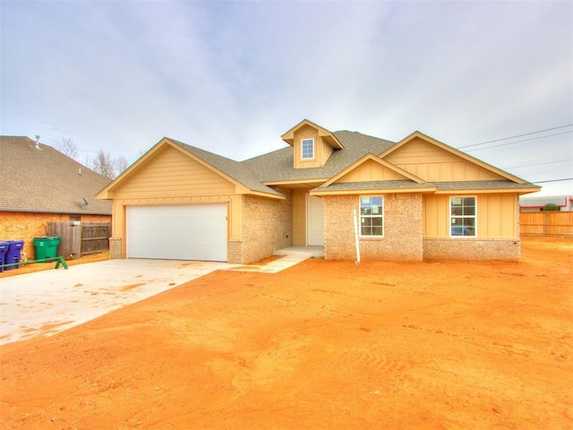 view of front facade featuring concrete driveway, an attached garage, fence, board and batten siding, and brick siding